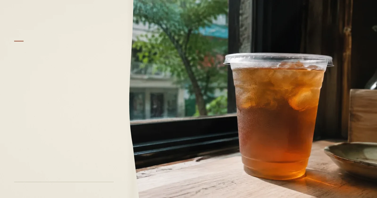 窗邊木桌上一杯透光的琥珀色冰茶，背景是模糊街景，呈現生活敘事的情境。